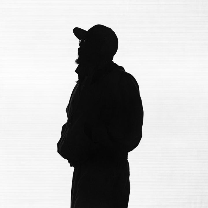 Silhouette of an unidentified person in profile wearing a cap and jacket against a light background