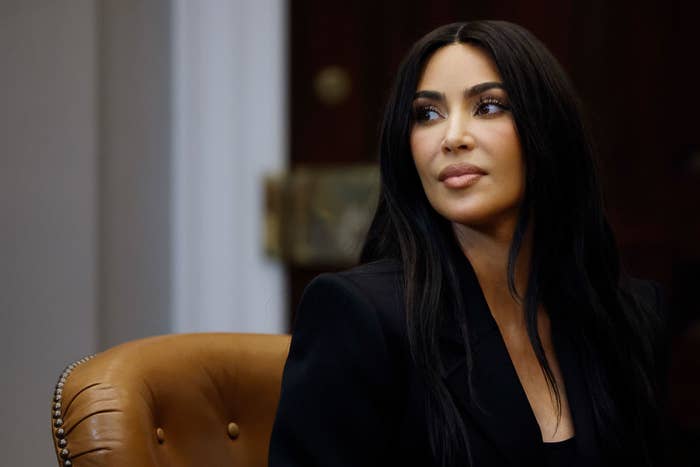 Kim Kardashian in a formal setting, wearing a sleek outfit, looking to the side