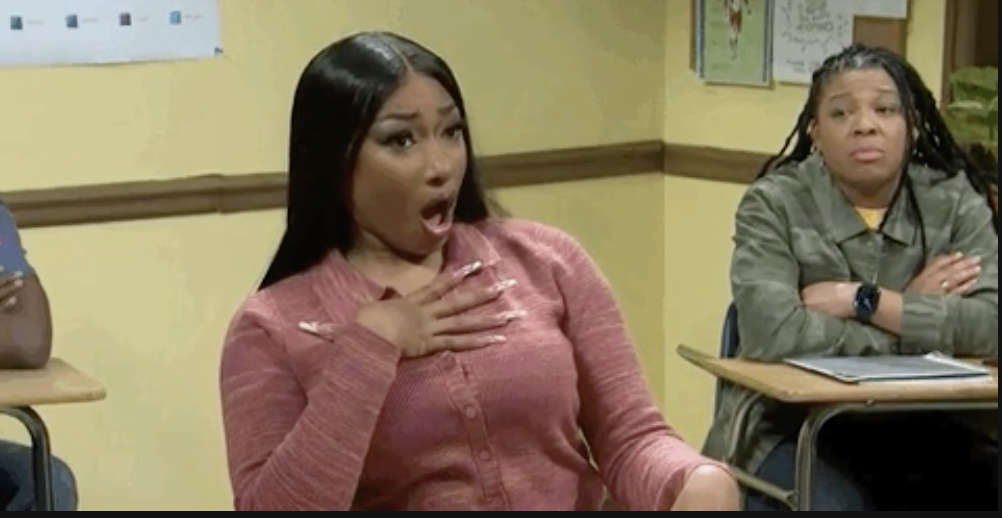 Two women in a room, one acting surprised with a hand on her chest