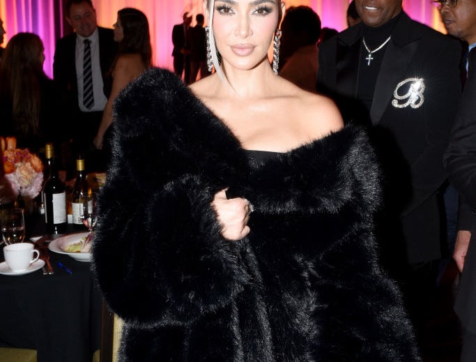 Kim Kardashian in a black fur coat at an event with &quot;HOMEBOY&quot; in the background