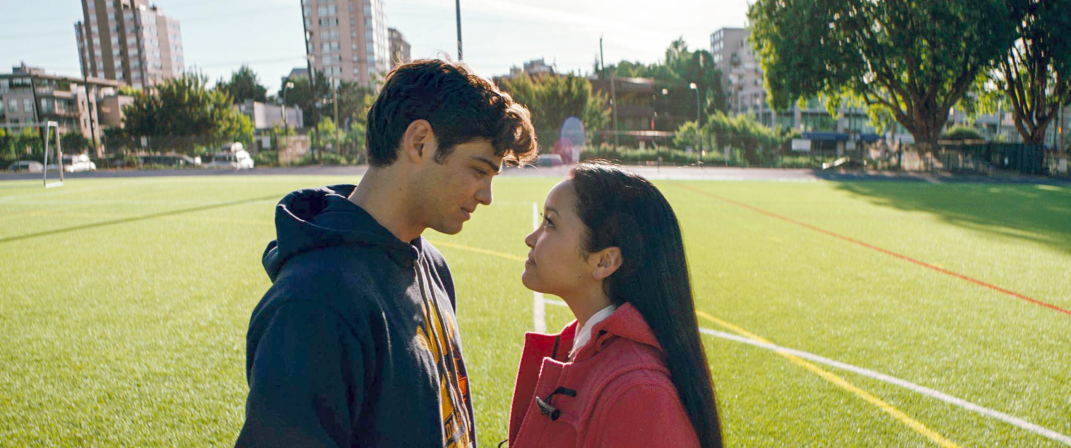 Peter and Laura Jean, standing on a grassy field, sharing a gaze with emotional tension