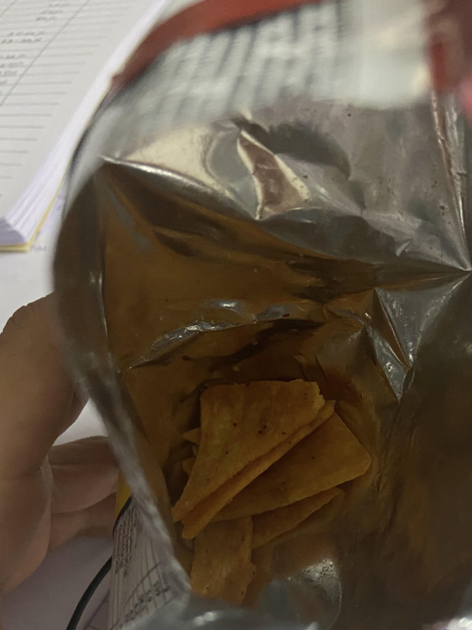 Person holding an almost empty chip bag, signifying the concept of receiving less product for the same price