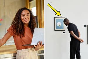 Person with laptop standing beside a counter; person observing framed artwork on a wall