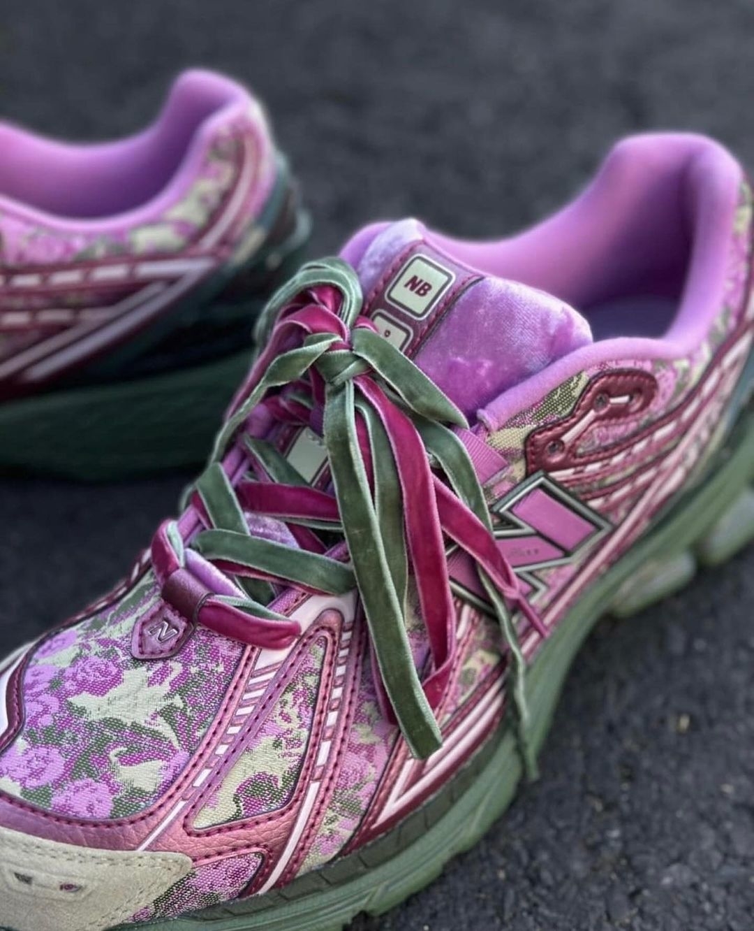 A pair of worn purple and green sneakers with elaborate patterns on pavement