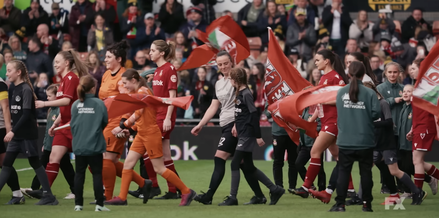 Soccer players walking onto the field with children and flag bearers before a match