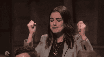 A woman with her fists up, smiling, making a celebratory gesture