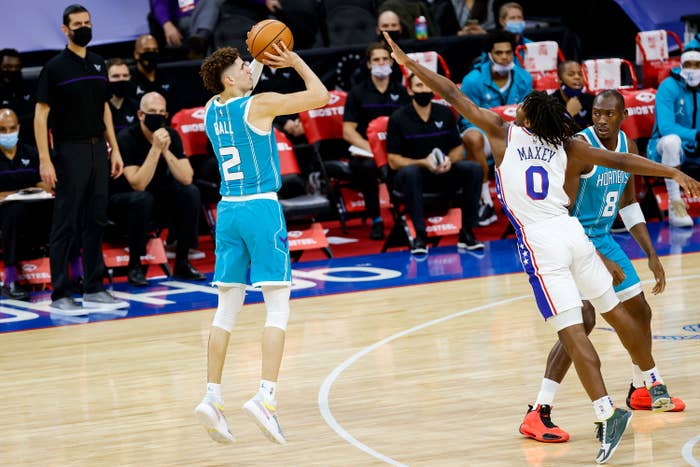 Basketball player in teal about to shoot with two opponents in white and blue defending
