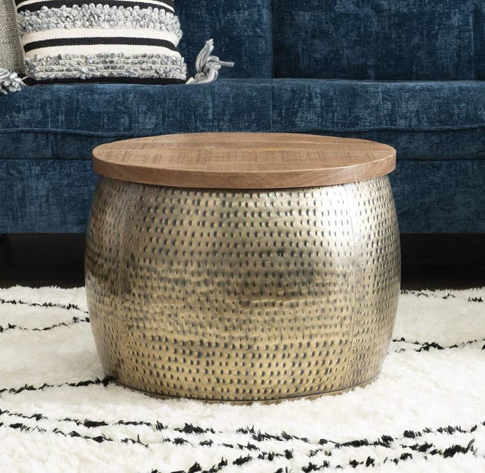 Hammered metal stool with wooden top on a white fluffy rug, furniture shopping