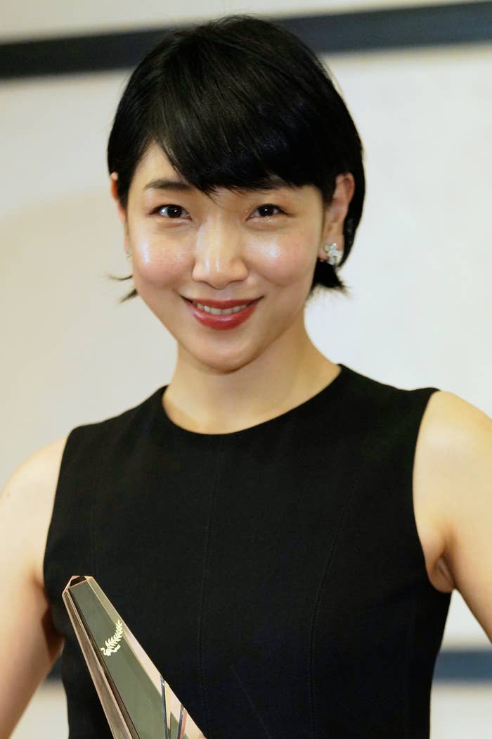 笑顔でカメラを見つめるショートヘアの女性がブラックドレスを着ています。