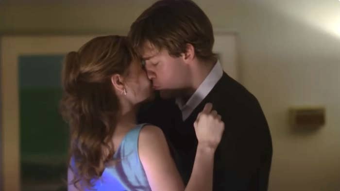 Two characters sharing a kiss, woman in blue dress, man in suit and tie