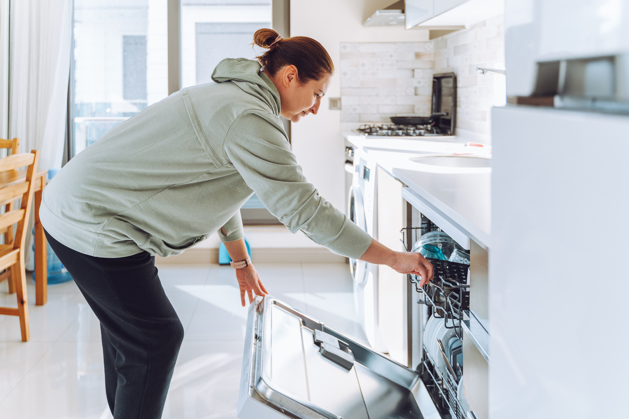 Woman loading a dishwasher in a kitchen setting