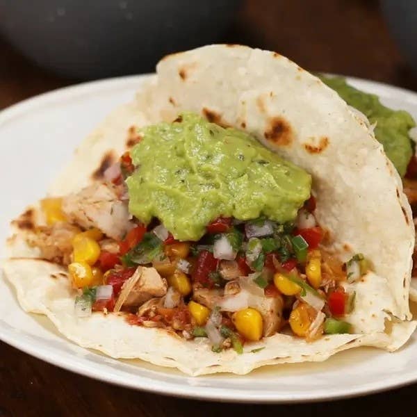 Grilled chicken taco with rice, corn salsa, and guacamole on a plate