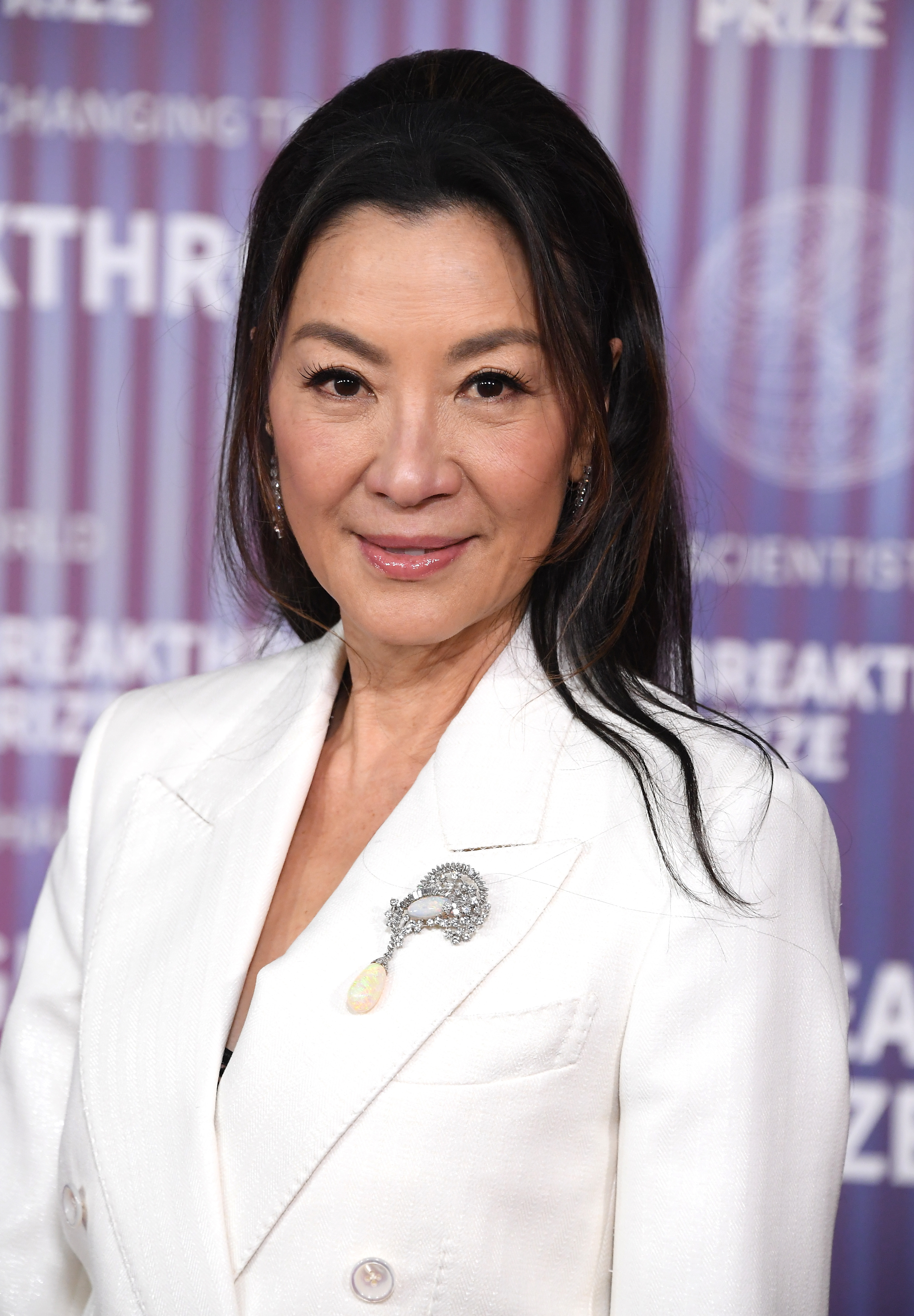 Michelle Yeoh in a white blazer with a brooch, posing at the Breakthrough Prize event