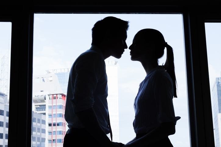 Silhouetted couple about to kiss by a window, cityscape in the background
