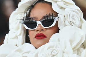 Person in avant-garde outfit with oversized flower details and dramatic eyelashes, wearing sunglasses