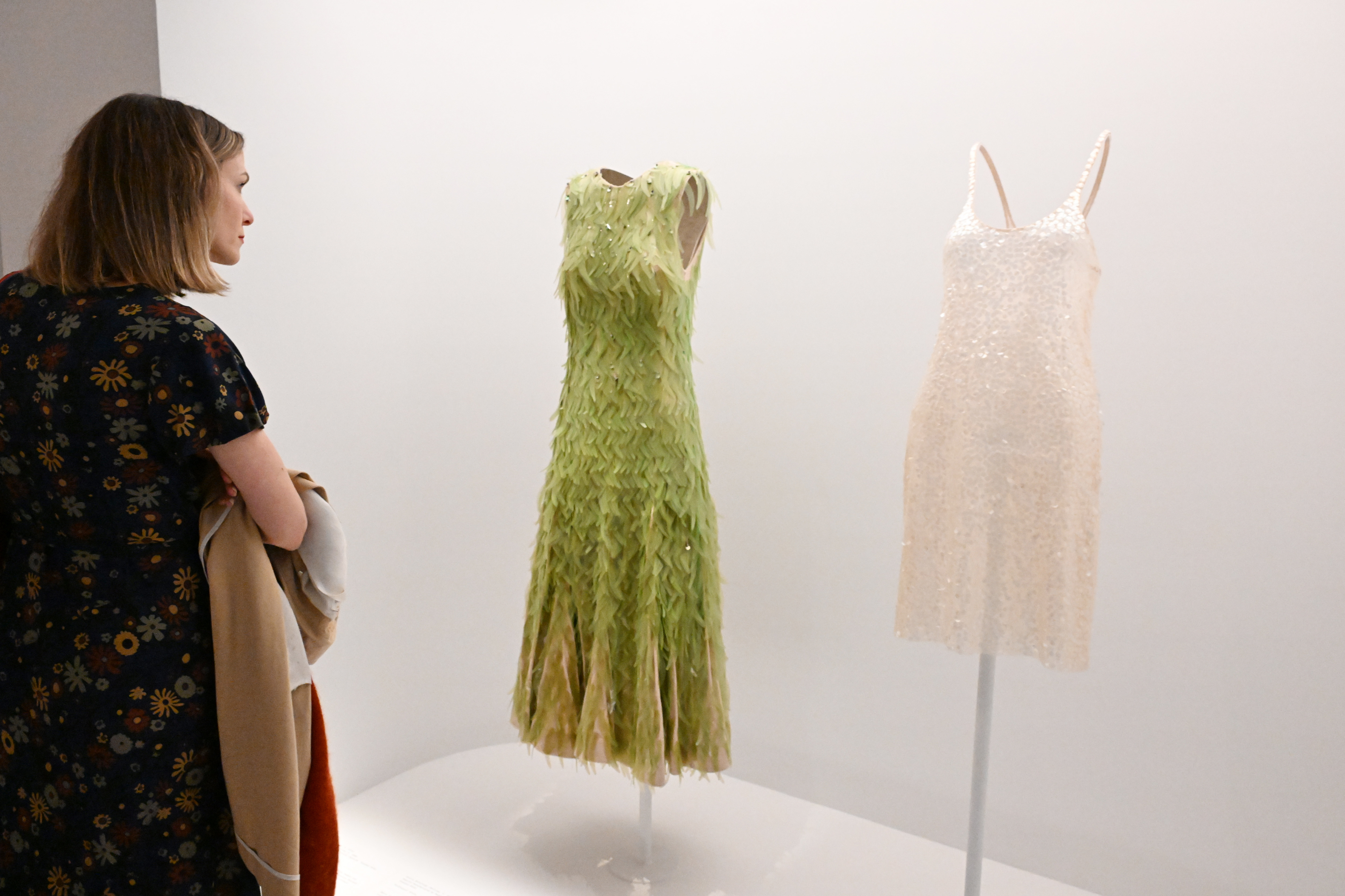 Woman viewing two elegant dresses on display