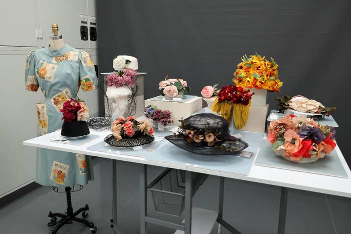 A collection of artistic hats with various decorations displayed on a table for an exhibit