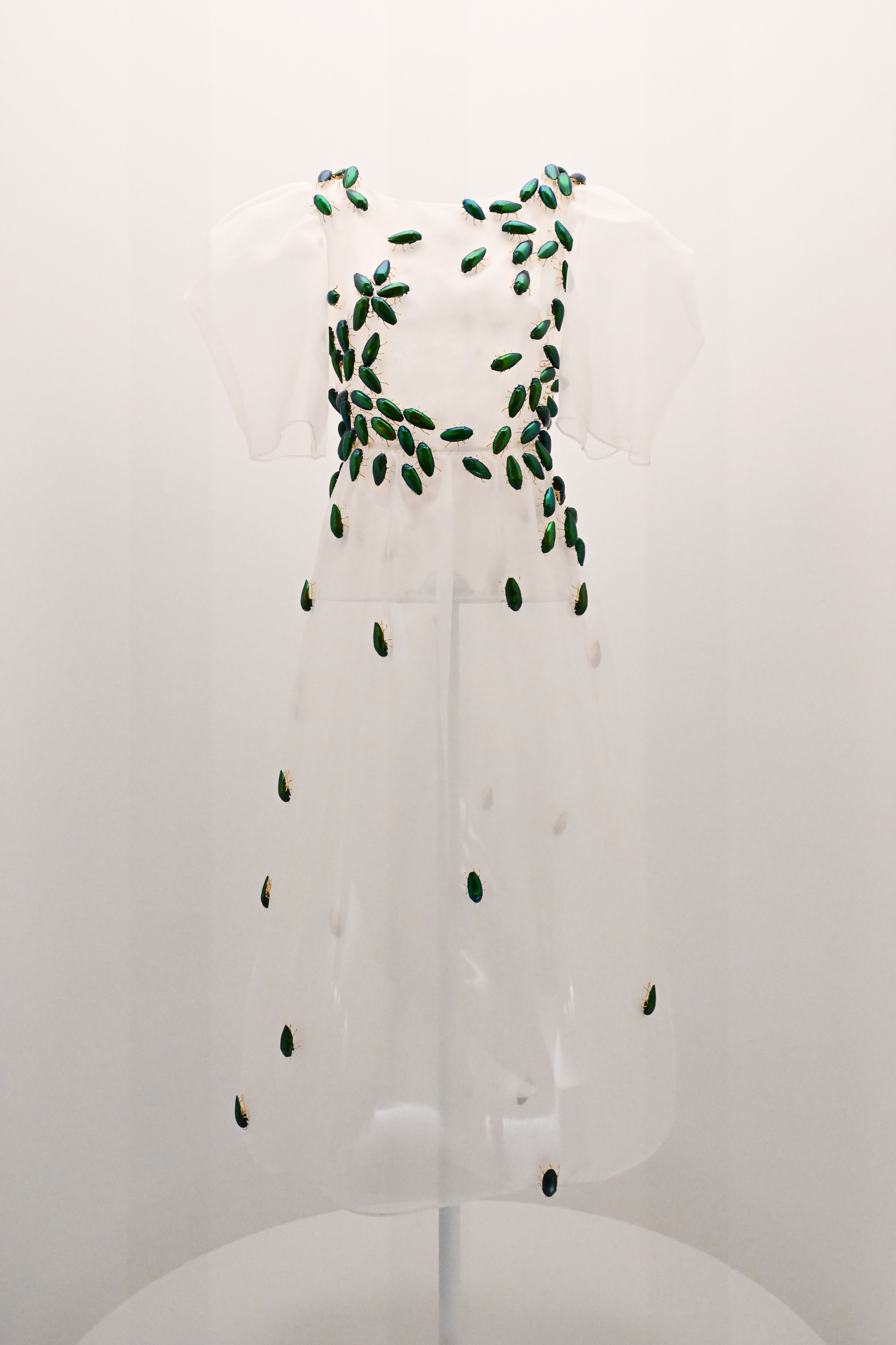 White dress with green leaf patterns on a mannequin against a white background