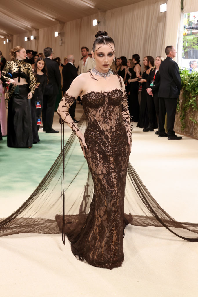 Emma Chamberlain in an ornate lace gown with sheer elements and a dramatic train at an event