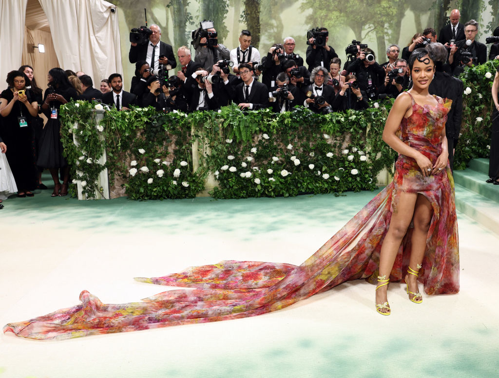 Maleah in floral gown with long train posing at event, photographers in background