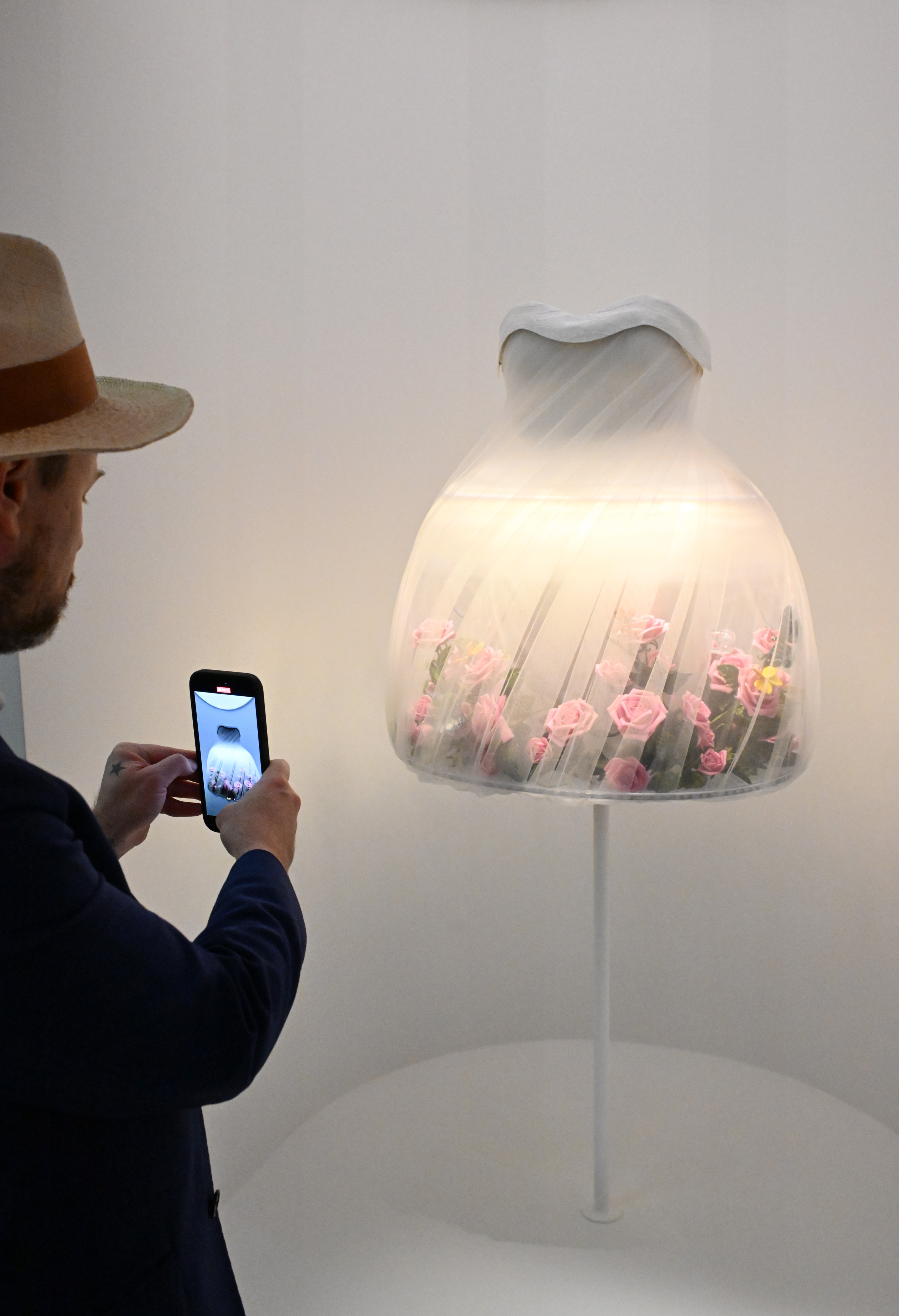 Person taking a photo of a lamp with a floral design inside the shade