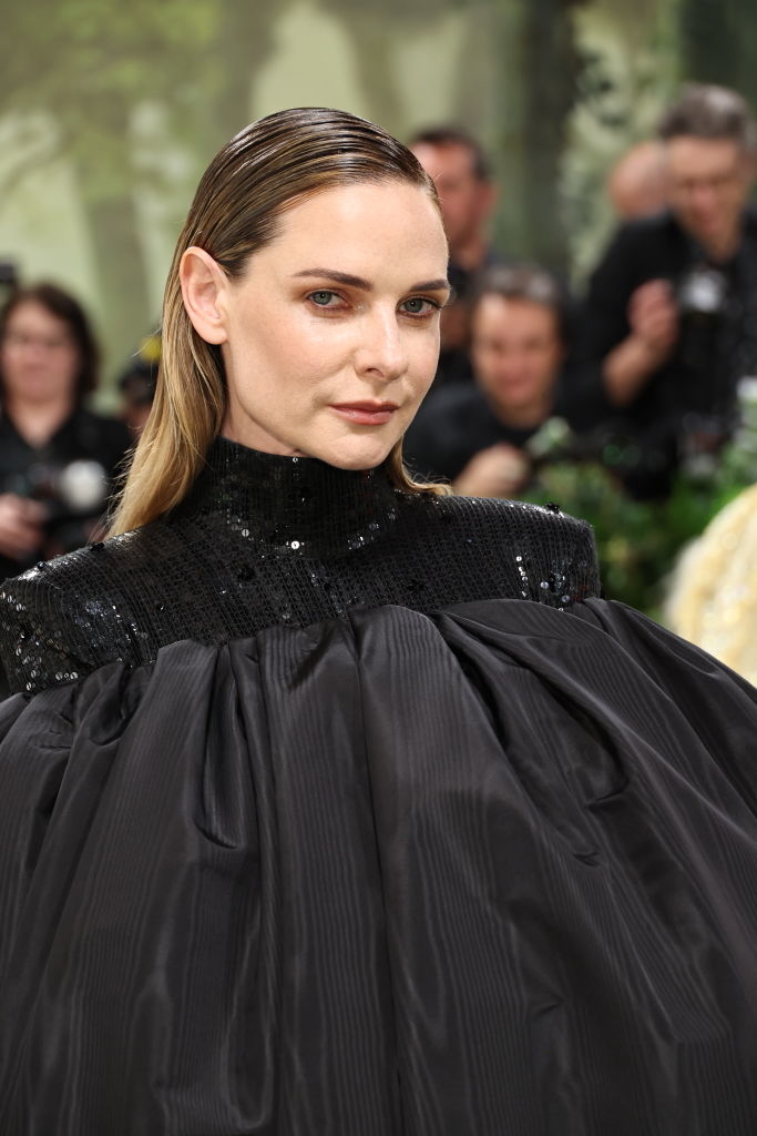 Rebecca Ferguson in a black textured gown with shimmering detail on neckline, looking forward at an event