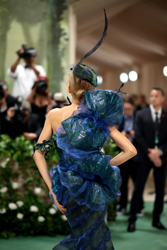 Zendaya at an event wearing an extravagant tiered gown with a large feathered headpiece