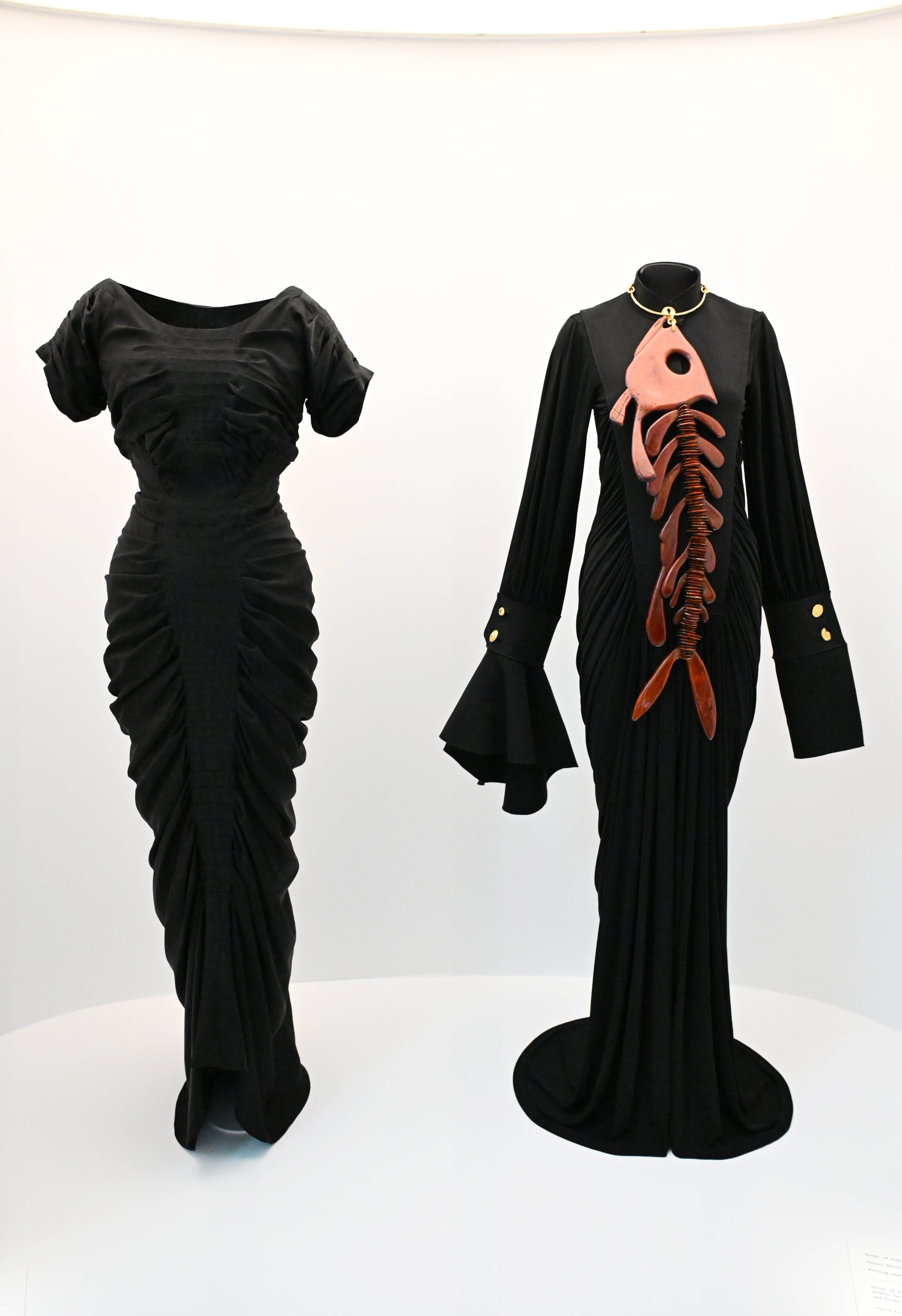 Two elegant vintage dresses on display, one with a ruffled skirt, the other with unique front lacing
