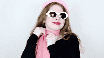 Persona con bufanda rosa y gafas de sol grandes en forma de corazón posando con actitud juguetona