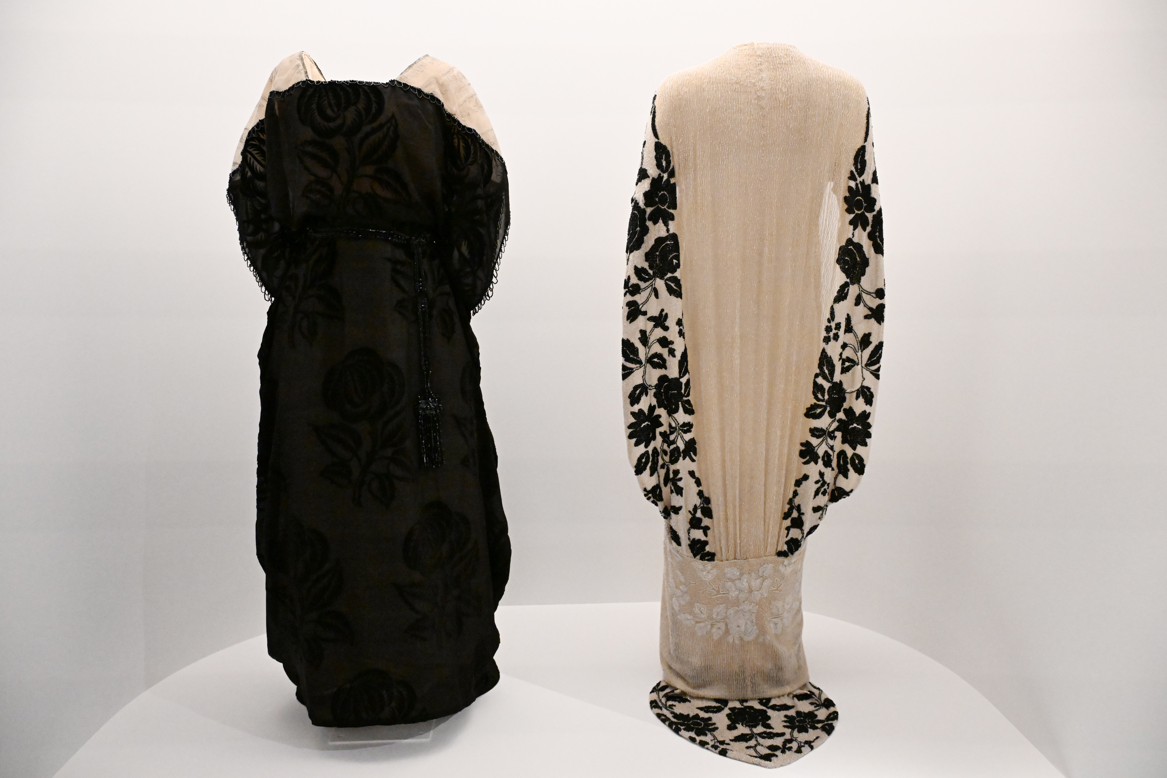 Two vintage dresses on display, one with floral patterns and one with lace detailing