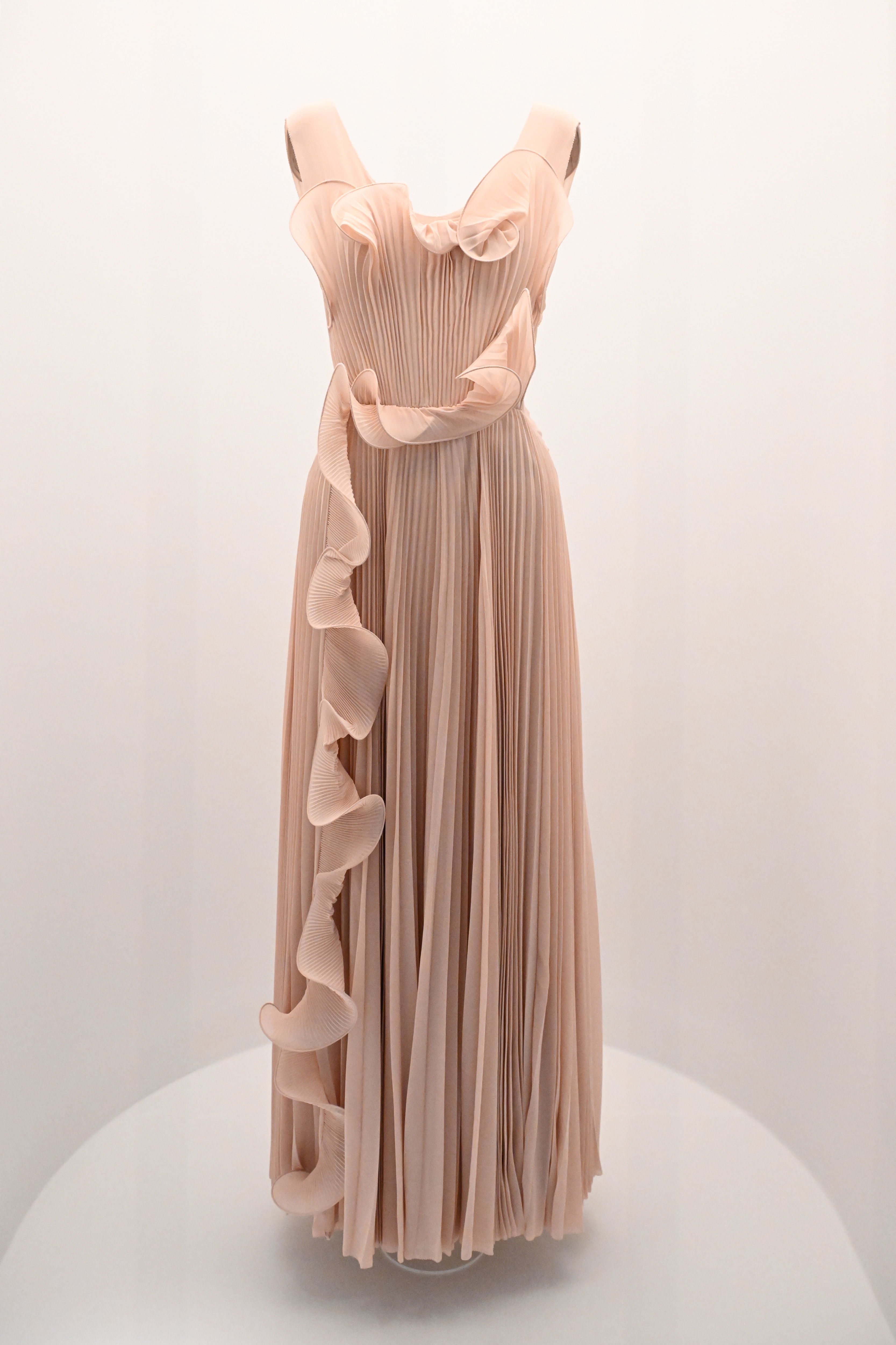 Elegant pleated evening gown with bow detail on bodice and ruffled trim, displayed on mannequin