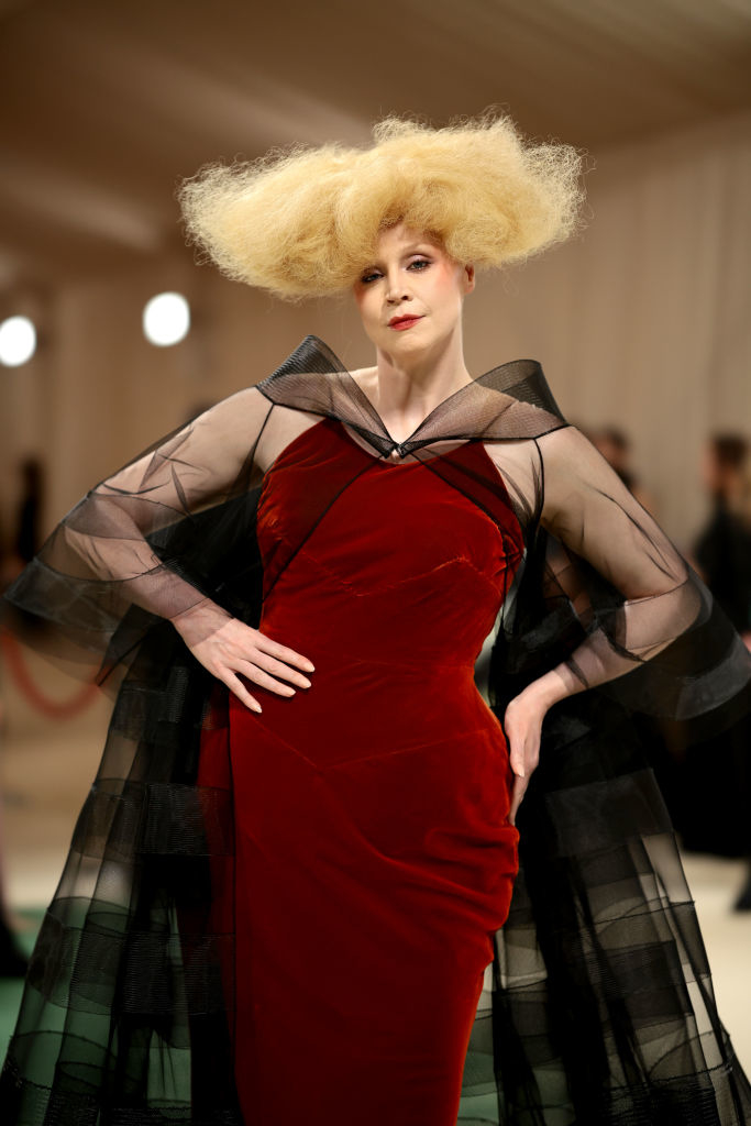 Gwendoline Christie in red dress and dramatic tulle collar, with voluminous updo, posing confidently