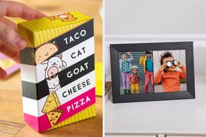 A hand holds a "Taco Cat Goat Cheese Pizza" card game next to a digital framed photo frame of children making funny faces