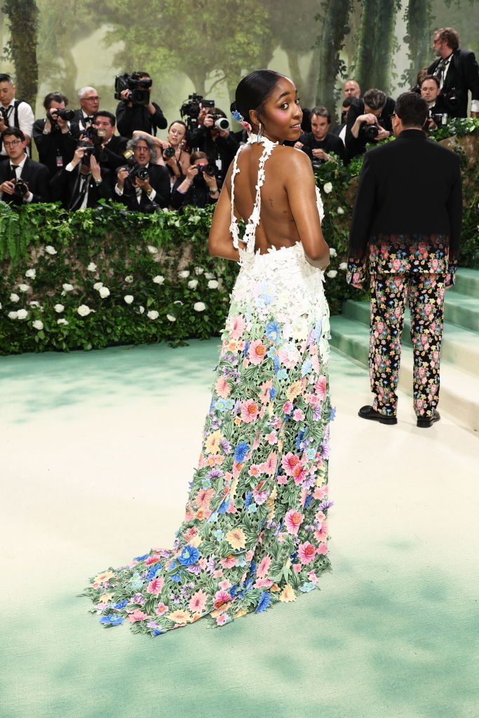 Ayo Edebiri on red carpet in floral dress with open back, photographers in background