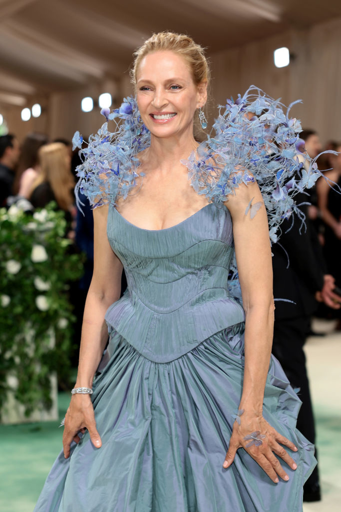 Woman in extravagant blue dress with shoulder embellishments poses on the red carpet