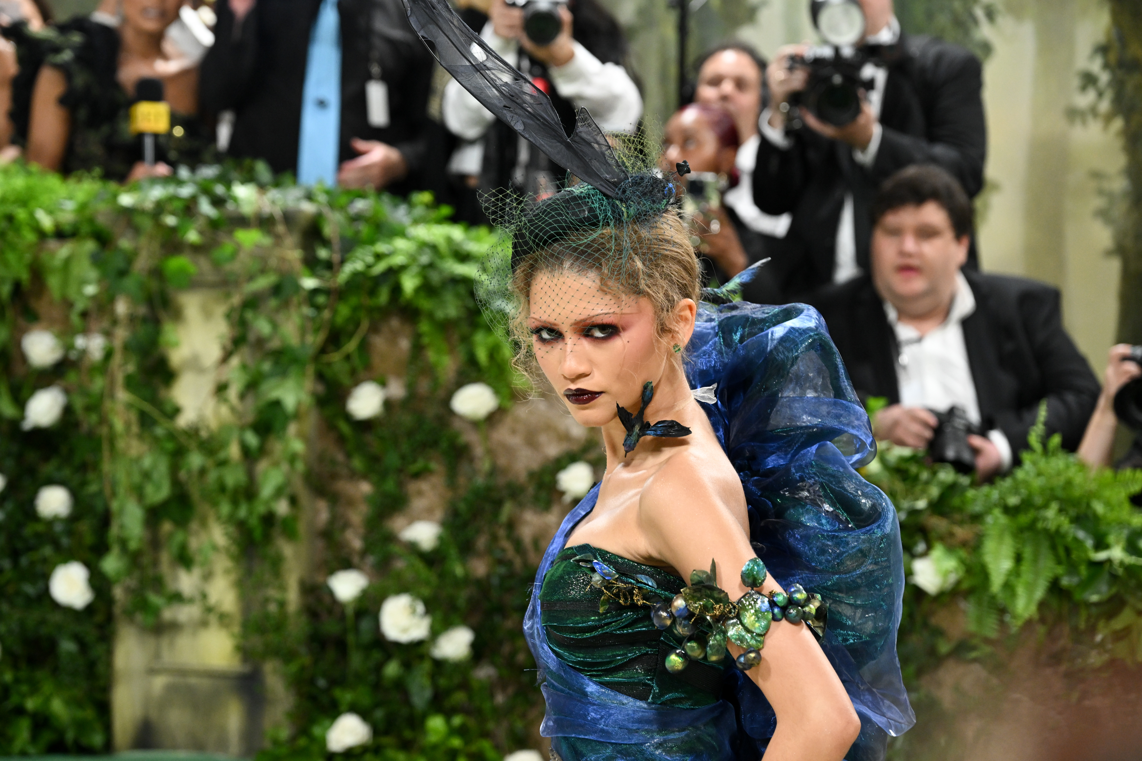 Zendaya in an avant-garde blue outfit with photographers in the background