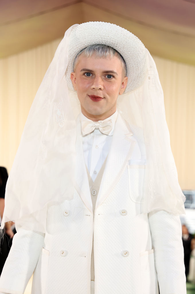 Cole Escola in an avant-garde white outfit with oversized jacket and tulle veil on head