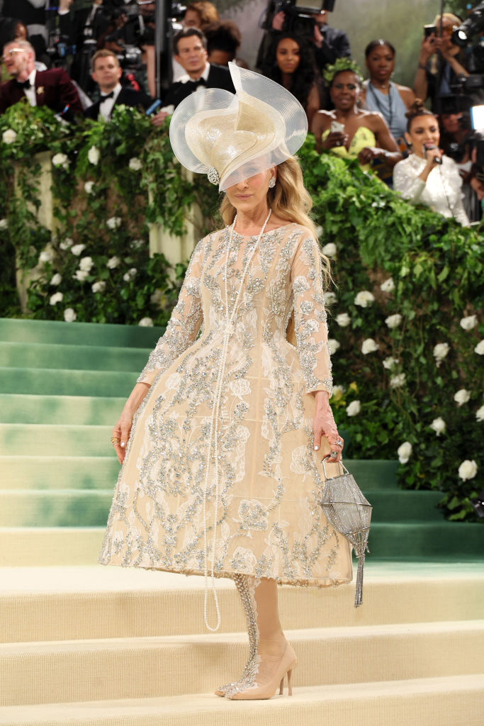 Sarah Jessica Parker in embellished knee-length dress and wide-brimmed hat walks on Met Gala stairs