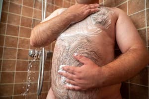 Person showering, partially obscured by a tiled wall, applying shampoo to their hair