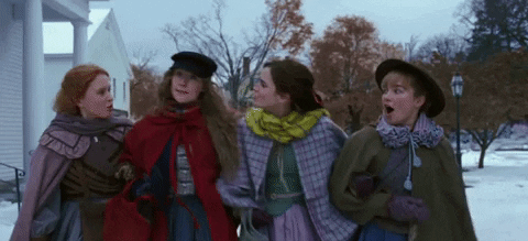 Four women from "Little Women" walk arm in arm,