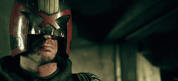 Judge Dredd wears helmet and fire reflects off the glass visor