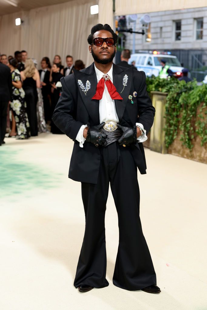 Leon Bridges black suit with winged embellishments and sunglasses on a carpeted event