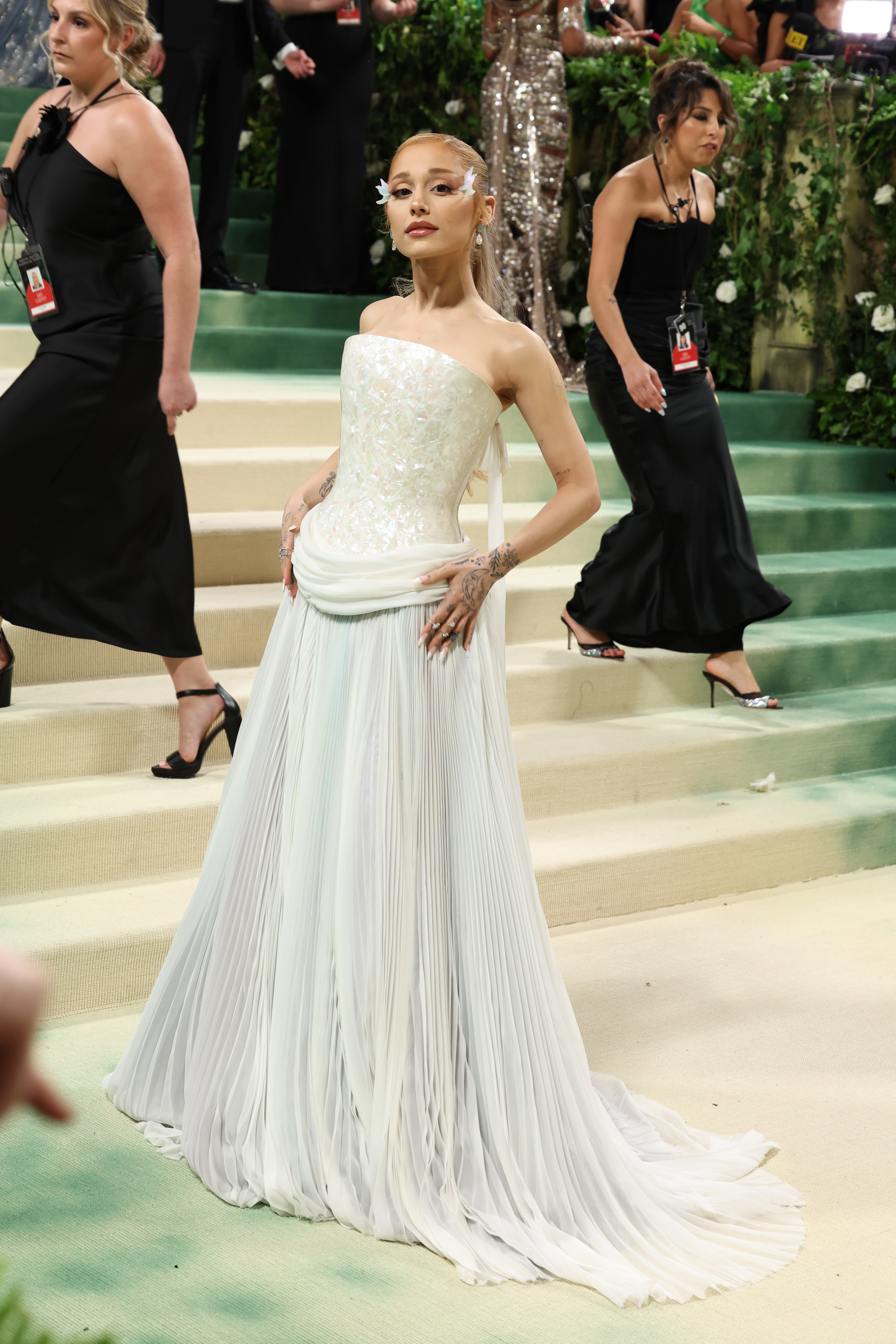 Mujer famosa en la Met Gala con vestido blanco plisado sin tirantes y guantes a juego