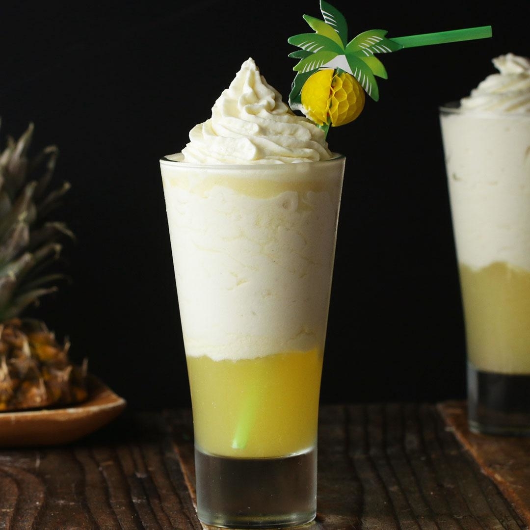 Pineapple float with whipped cream and decorative palm tree straw in a glass
