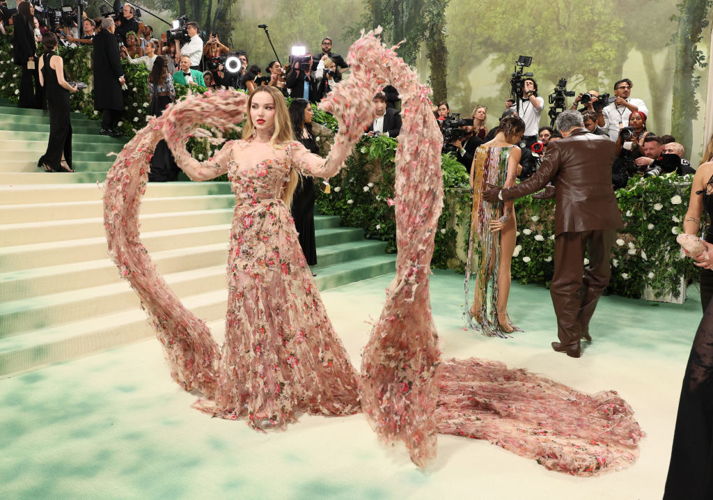 Dove in a floral dress with a long train posing on stairs, photographers in the background