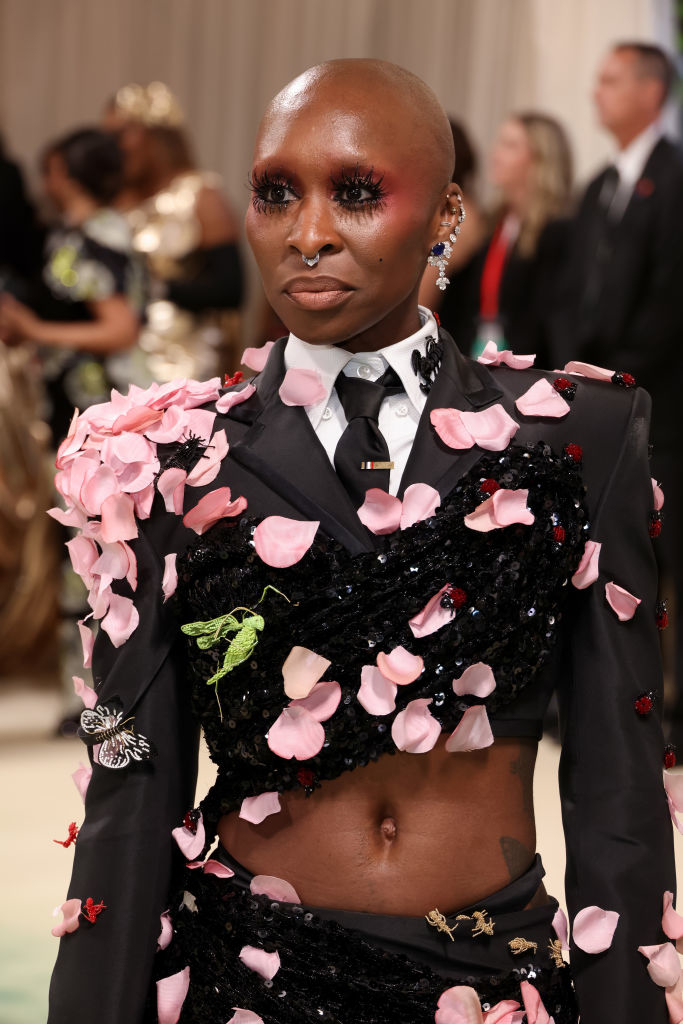 Cynthia Erivo in a sequined outfit with pink petal accents, tie, and butterfly brooch