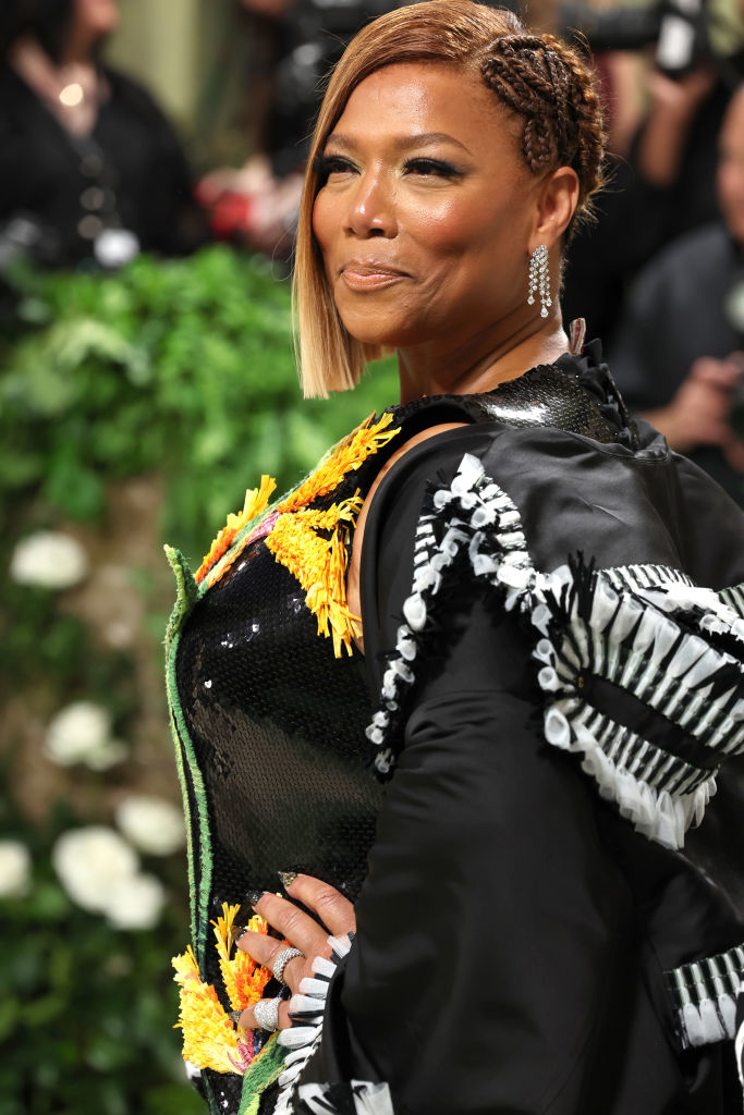 Queen Latifah in a unique black outfit with floral details, posing at an event