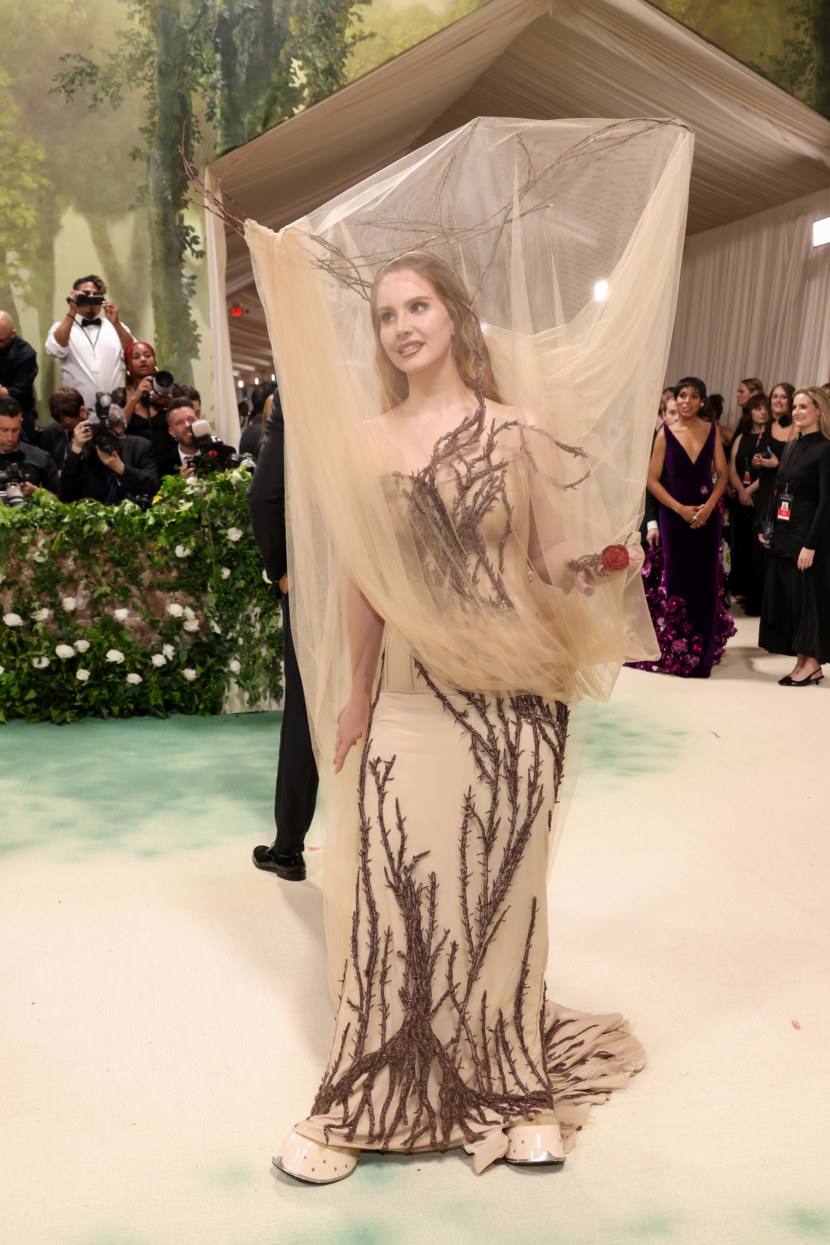 Mujer en evento de gala con vestido transparente con bordados que imitan ramas