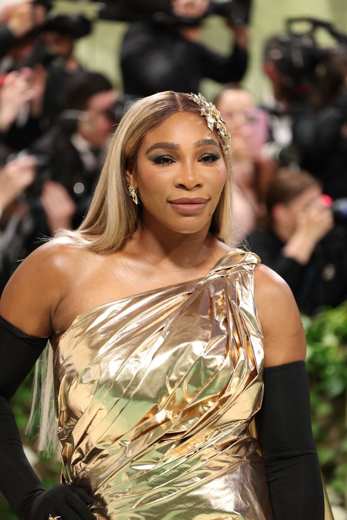 Serena Williams in a golden one-shoulder gown with a headpiece at an event