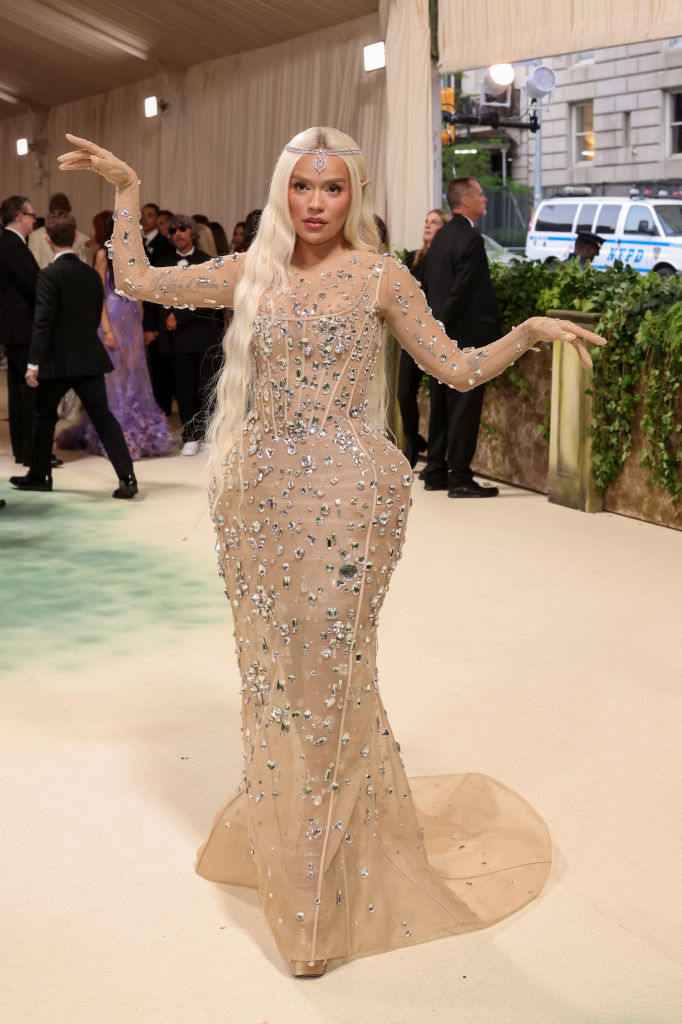 Karol in a fitted, bejeweled gown with long sleeves and a headpiece